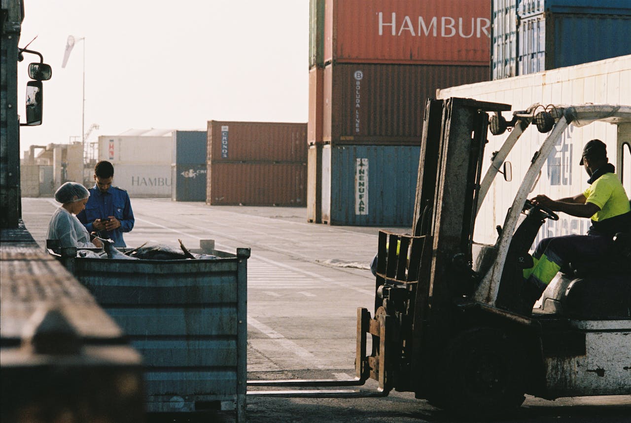 The Art of Drawing Readers In: Your attractive post title goes here Workers operating a forklift in a shipping container yard at Praia port, Cabo Verde.